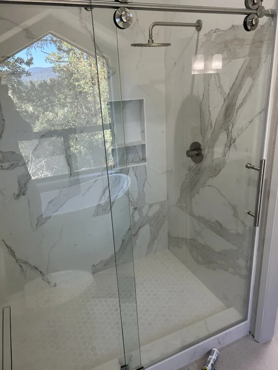 Glass shower enclosure with marble walls and built-in niche