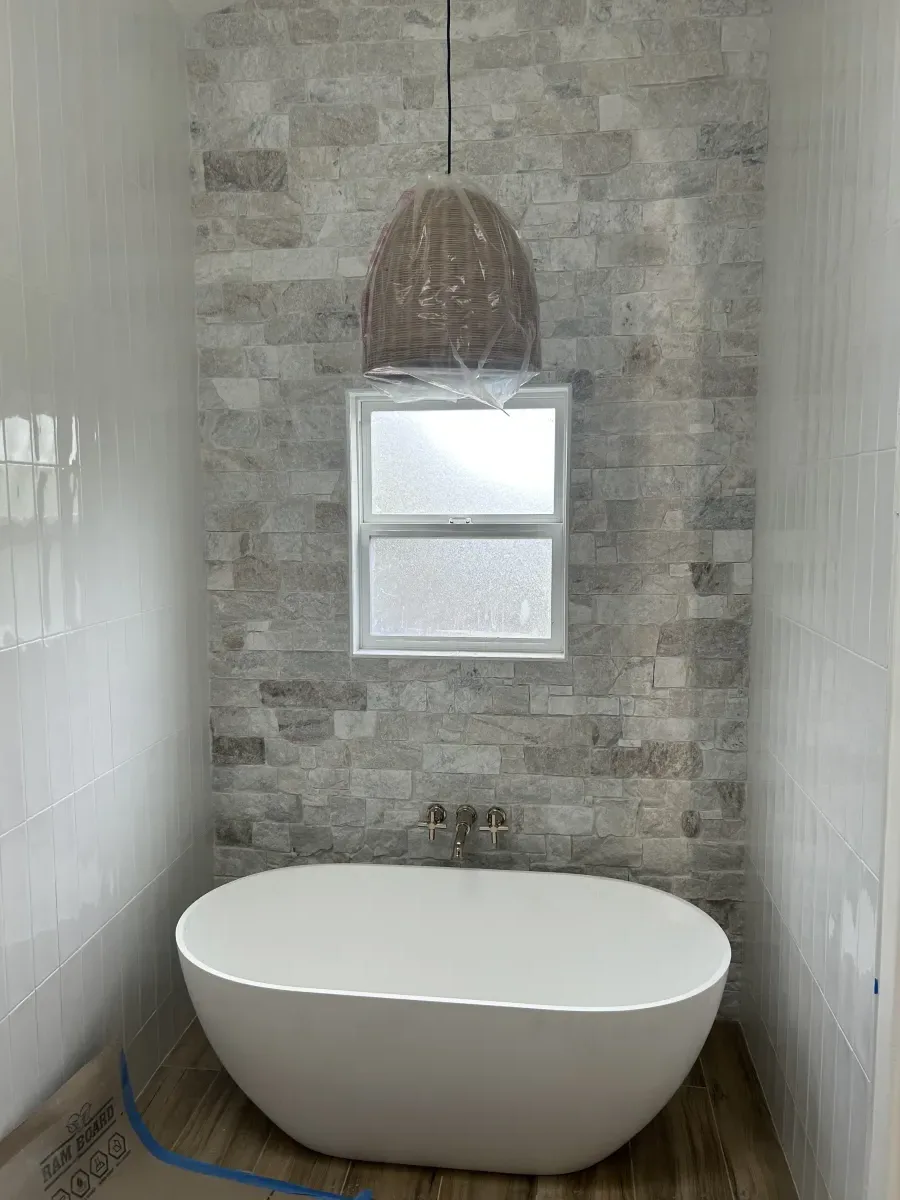 Freestanding soaking tub with stone accent wall and wall-mount faucet