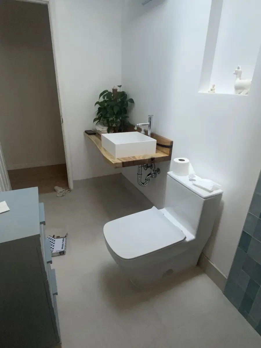 Bathroom with modern toilet, floating shelf, and teal tile accent